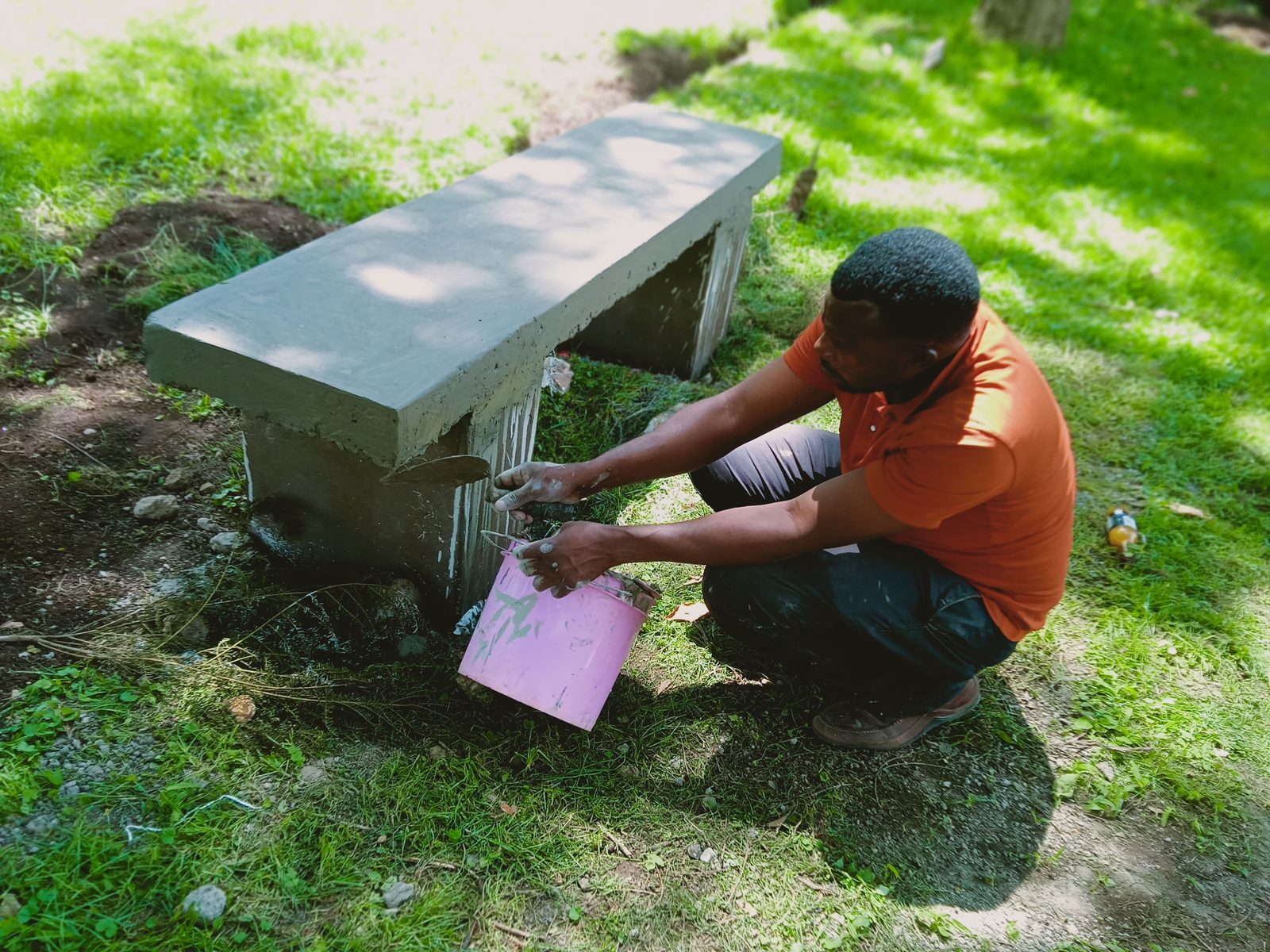A workman finishing a cast concrete bench installed in a community park