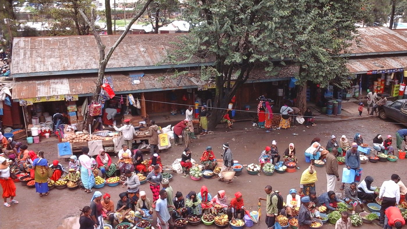 Traders and shoppers filling the open trading area of a local public market in Arusha