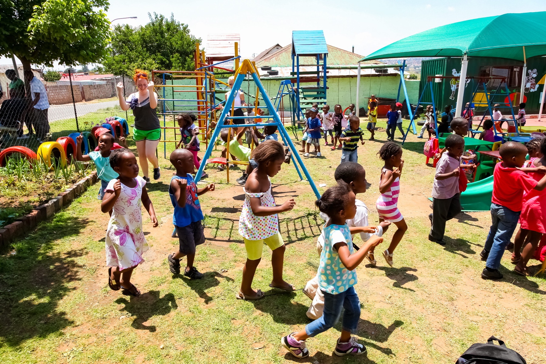 Young children playing on climbing frames and swings in a preschool playground