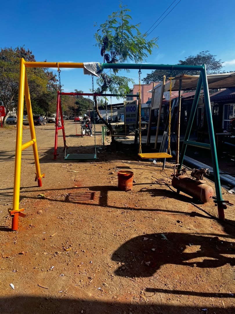 Swing frames painted in bright colours at the fabrication yard, waiting to go out to schools